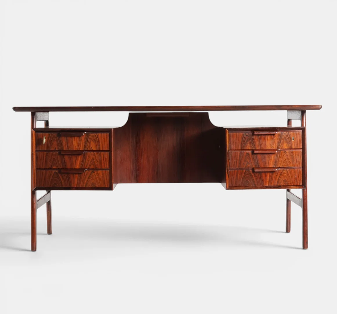 GUNNI OMANN. Fritstående skrivebord af palisander, front med seks skuffer, bagside med opbevaringsrum. Udført hos Omann Junior, Ølholm, model "75." Danmark, 1960'erne. — Desks — Woxholt Auktioner