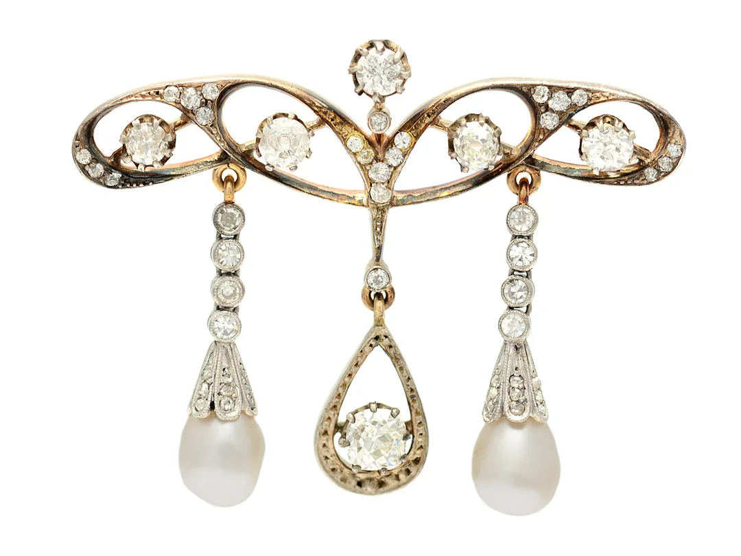 BROSCH, silver/18K guld/platina, 6 gammalslipade diamanter ca 1,75 ctv, ca W-Cr(H-J)/SI, orientaliska pärlor ca 7-7,5 mm, 8 åttkantslipade diamanter ca 0,24 ctv, 20 gammalslipade diamanter ca 0,20 ctv, 18 rosenslipade diamanter, 2 glasstenar, Jugend, mått 5 x 3,8 cm, vikt 13,3 g, en diamant är skadad. — Smycken/Brosch — Kaplans