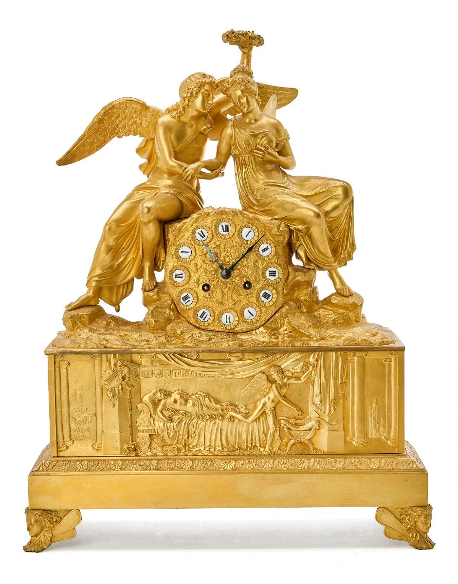 A French late Empire mantelpiece clock in gilt bronze, case with seated Cupid and Psyche, chapter ring with white enamel plaques with black Roman numerals. Early 19th century. H. 47 cm. W. 38 cm. D. 14 cm. — Clocks & watches/Mantel & Wall Clocks — Bruun Rasmussen