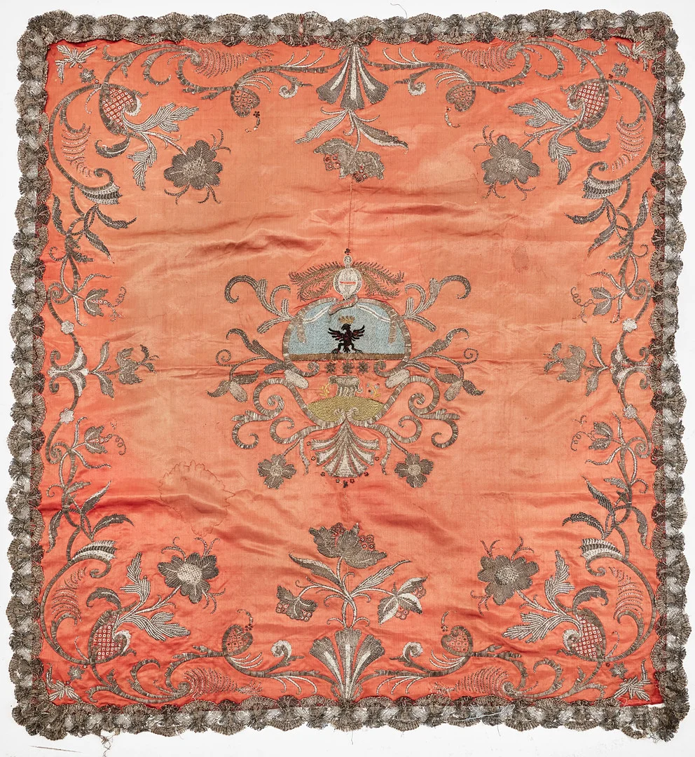 PÄLL, ca 1730-1750-tal, botten i varmt rosa sidensatin, kanter med blomsterbårder i reliefbroderi i silvertråd och silverlan, med paljetter, spegelns mitt med delat vapen bestående av krönt örn samt lamm, upptill med riksäpple. — Textiles — Stockholms Auktionsverk Magasin 5
