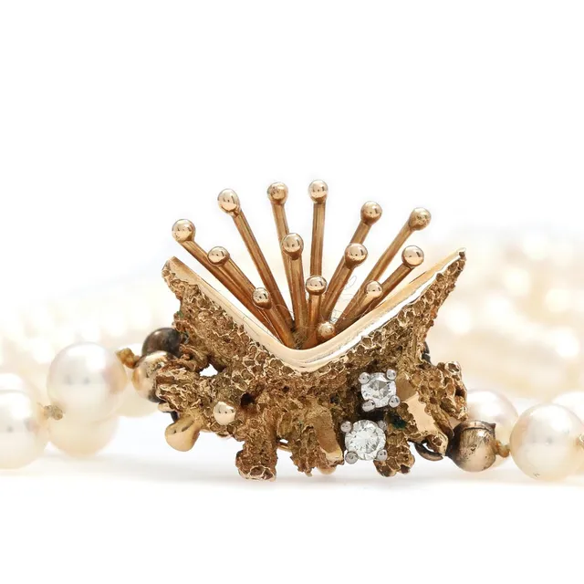Diamond clasp set with two brilliant-cut diamonds, mounted in 14k gold with double-stranded pearl chain. Pearl diam. 6–6.5 mm. L. 50–52 cm.