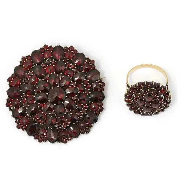 A jewellery collection comprising of a ring and a brooch set with numerous faceted garnets, mounted in 14k gold and yellow metal. Size 56.5. (2)