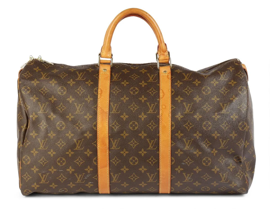 A “Keepall 50” travel bag of brown monogram canvas with brown leather trimmings, gold tone hardware, two handles, one zipped compartment with brown fabric lining. H. 30 x W. 50 x D. 40 cm. 1995. — Designer Handbags & Fashion/Designer Handbags — Bruun Rasmussen