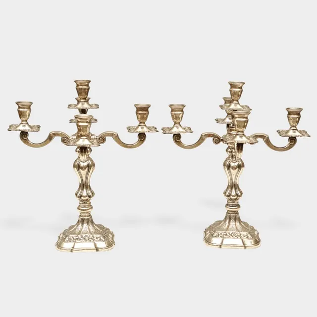 Pareja de candelabros de cinco luces en plata española punzonada. Decoración cincelada y repujada de motivos vegetales.