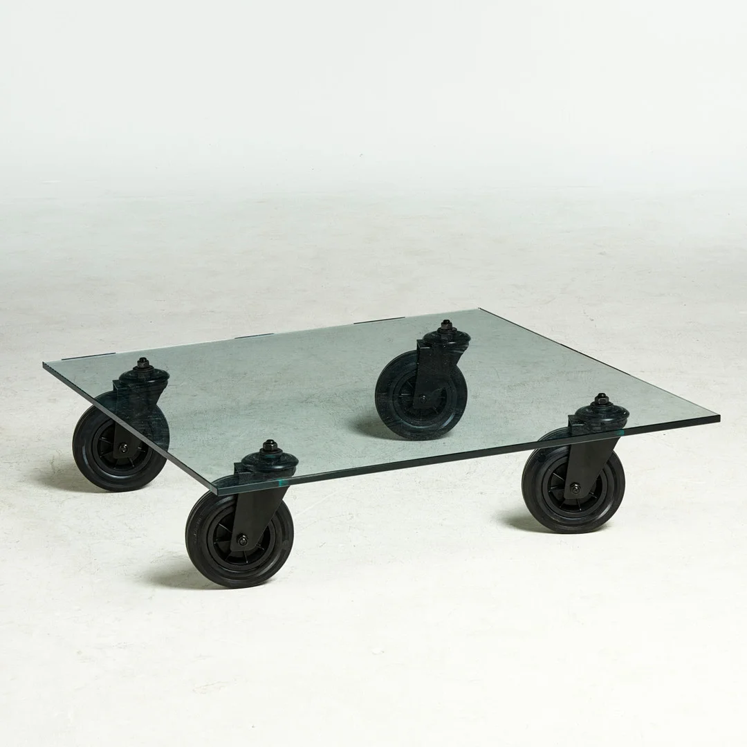 GAE AULENTI. "Tavolo con Ruote", soffbord, FontanaArte, Italien, samtida, modellen ursrpungligen formgiven 1980, bordsskiva i glas, hjul av svartlackerad metall och gummi. — Tables — Stockholms Auktionsverk Sickla