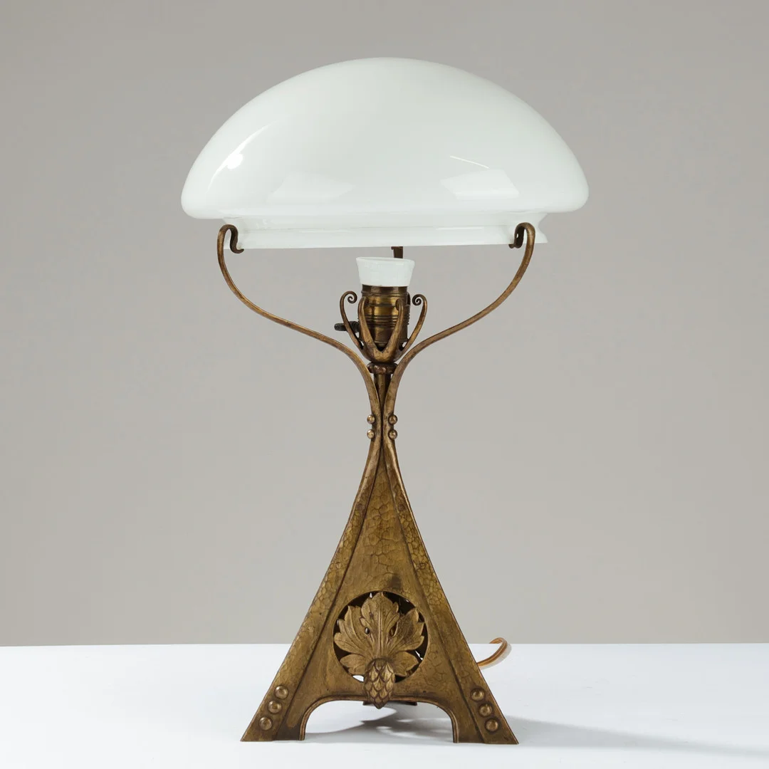 JUGENDSTIL: Skulpturel bordlampe af hammerslået messing dekoreret med relieffer af grankogler og blade, europæisk lampeproducent, 1900-tallets begyndelse. — Table Lamps — Palsgaard Kunstauktioner