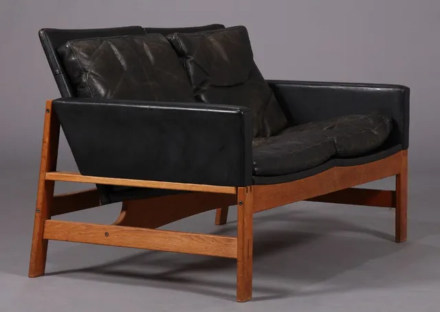 Dansk møbelproducent. Fritstående 2-pers. sofa på tel af egetræ, beklædt med sort læder