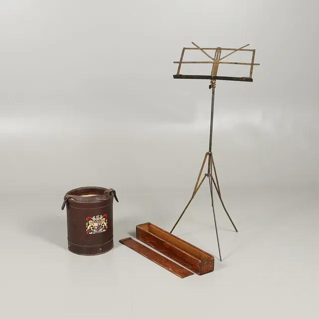 A VINTAGE FOLDING MUSIC STAND AND A LEATHER SHOT/CORDITE STYLE BUCKET.