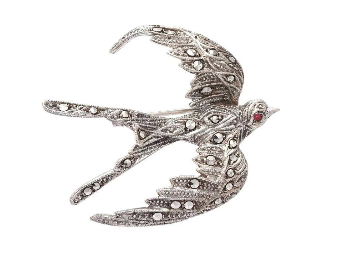 BROSCH, fågel, silver, markasiter, röd glassten, mått 37x32 mm, vikt 6,6 g, litet skada på glasstenen. — Smycken/Brosch — Kaplans