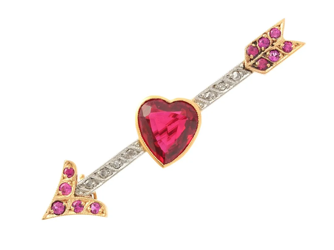 BROSCH, 18K guld/vitguld, hjärtslipad syntetisk rubin, syntetiska rubiner, gammal- och rosenslipade diamaneter, längd 58 mm, vikt 8,6 g, en av de mindre syntetiska rubinerna och en rosenslipad diamant är skadad. — Smycken/Brosch — Kaplans