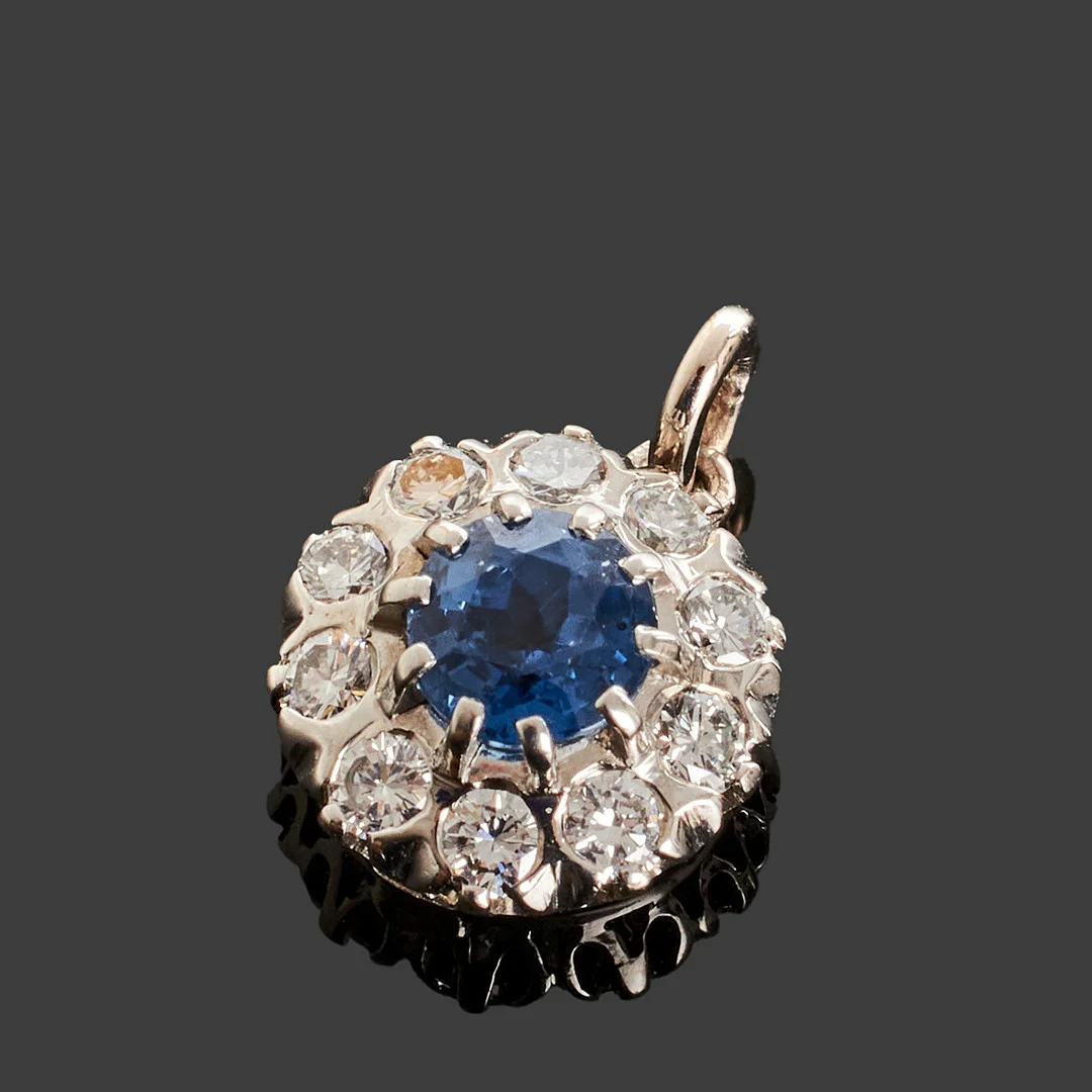 CARMOSÉHÄNGE, 18k vitguld, centrerad safir ca 0.70ct bekransad med briljantslipade diamanter totalt ca 0.30ct. — Brooches & Pendants — Crafoord Auktioner Stockholm