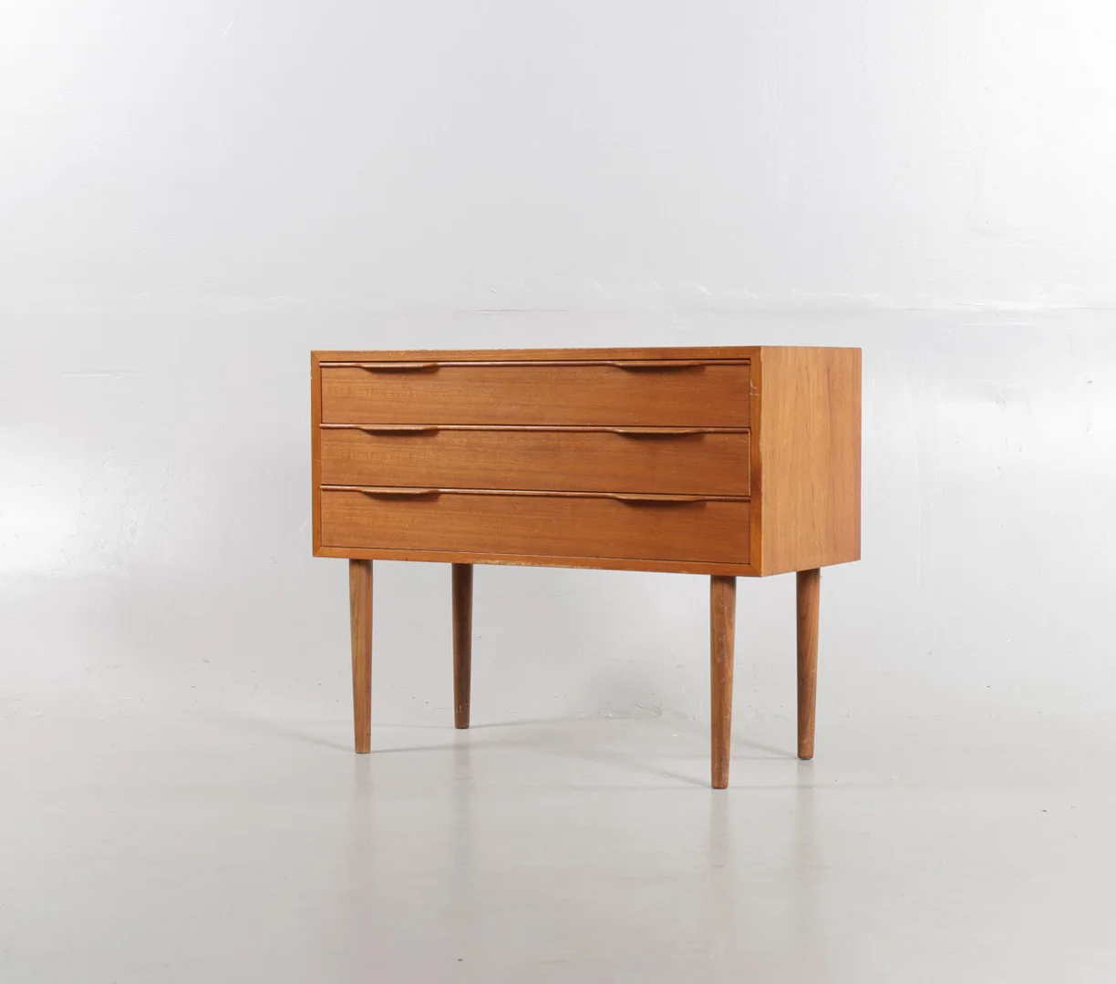 DANSK MØBELDESIGN. Kommode af teak, front med tre skuffer, monteret med tilspidsede ben, 1960'erne. — Chests of drawers — Woxholt Auktioner