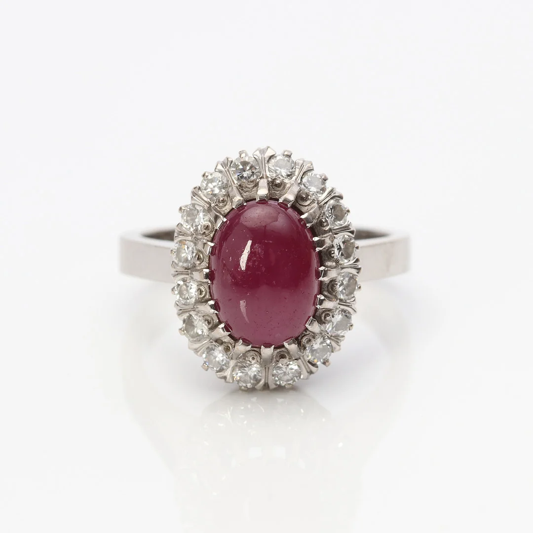 RING, CARMOSÉMODELL. 18k vitguld med en cabochonslipad rubin och briljantslipade diamanter. — Rings — Skånes Auktionsverk