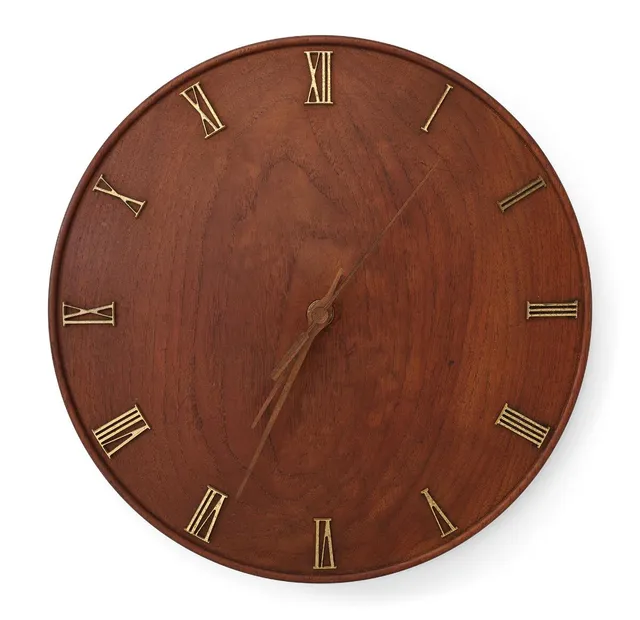 A circular solid teak wall clock with brass Roman numbers and teak hands. 1930s. Later Quartz movement. Diam. 28.5 cm.