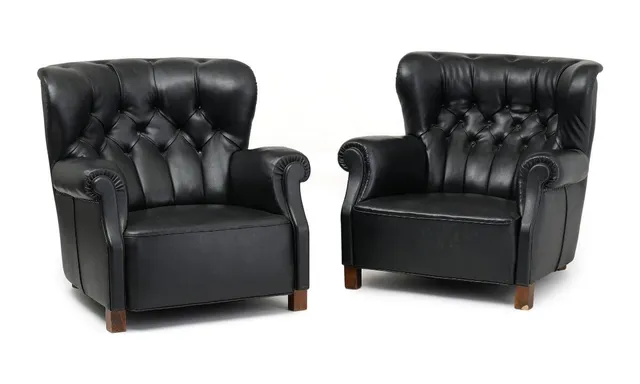 A pair of easy chairs with stained beech legs. Seat, sides and back upholstered with black imitated leather. Manufactured by Fritz Hansen, 1940s. (2)