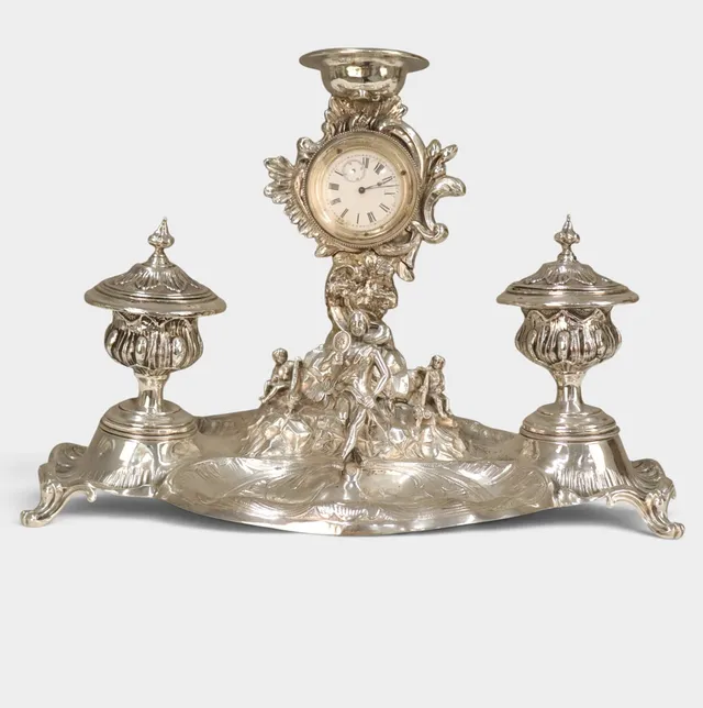 Escribanía con reloj en plata repujada. Estilo historicista. Principios del siglo XX.