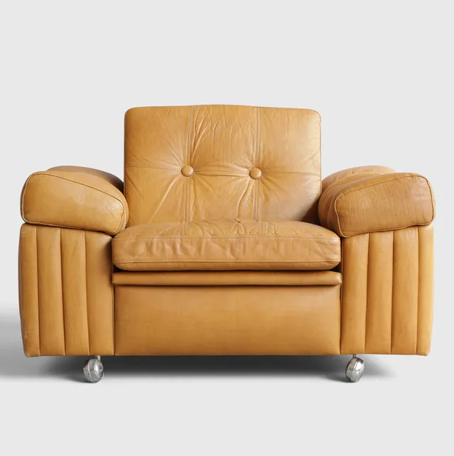 SVEND SKIPPER. TILSKREVET. Lavrygget lænestol betrukket med knapsyet læder, løse hynder i sæde og ryg, for- og bagside med hjul. Antageligvis udført hos Skipper Furniture. Danmark, 1970'erne.