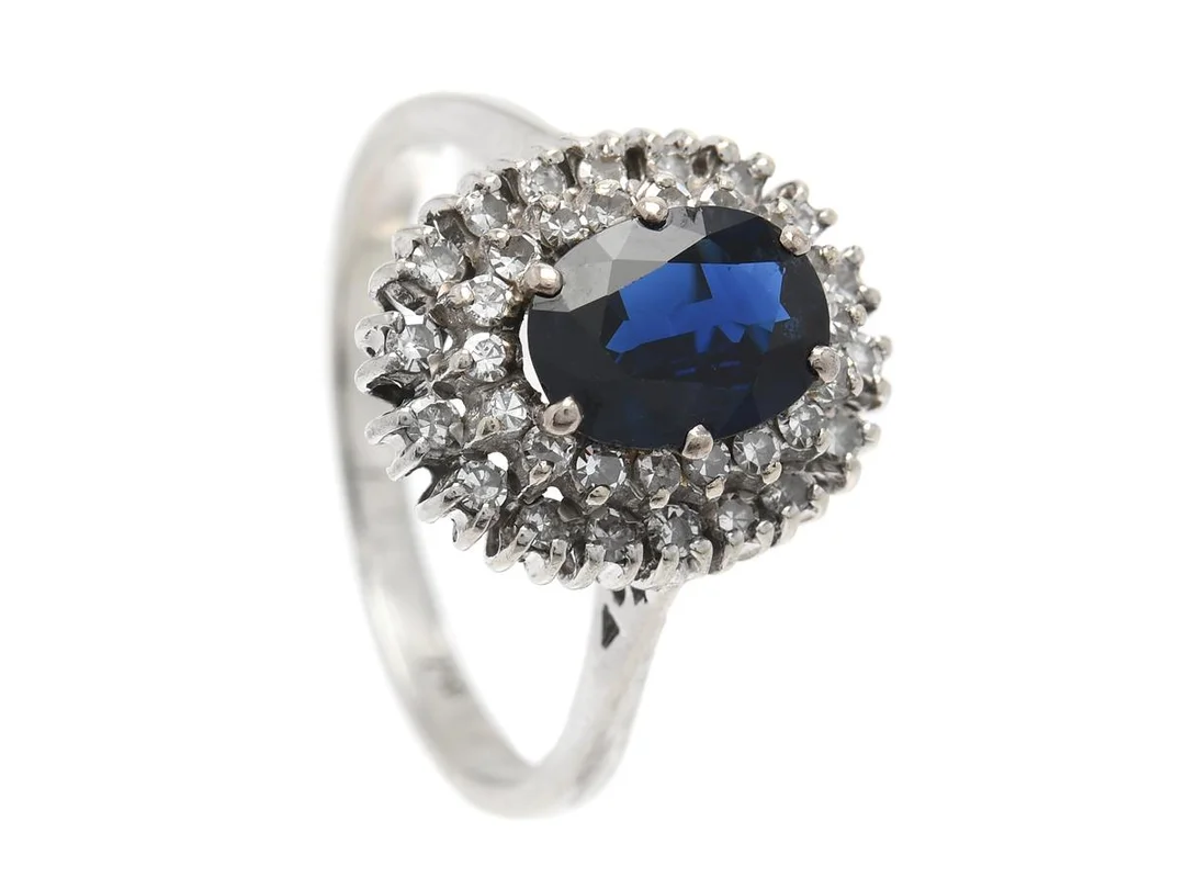 CARMOSÉRING, 18K vitguld, ovalslipad blå safir, 36 åttkantslipade diamanter, stl 18,5 mm, vikt 4,6 g, svaga fattningar, safiren har nagg, skador på galleriet. — Smycken/Carmoséring — Kaplans