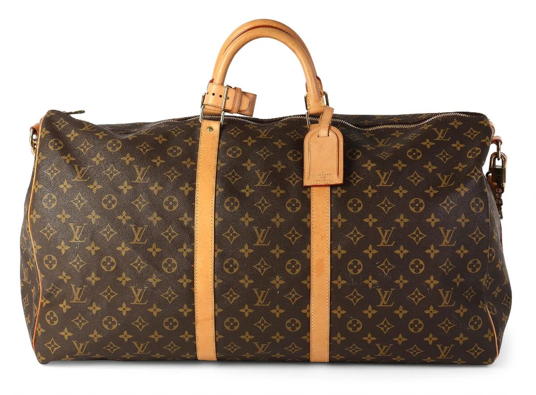 A “Keepall 60” travel bag of brown monogram canvas with brown leather trimmings, gold tone hardware, two short handles, one adjustable shoulder strap and one zipped compartment with brown fabric lining. Accompanied by luggage tag. H. 30 x W. 60 x D. 40 cm. 2000. — Designer Handbags & Fashion/Designer Handbags — Bruun Rasmussen