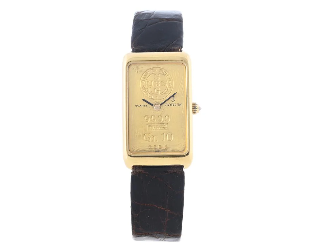 CORUM, Ingot Watch, Cal 602, Verk nr. 202315, Nr. 3905, Serie nr. 363501, Ref nr. 420056, Boett nr. 42400, unisex, 21 x 34 (36) mm, 18K guld, quartz, safirglas, urtavla i 10 gram guld, krona med diamant, läderband, originalspänne i doublé, cert, februari 1983, etui. — Klockor/Corum — Kaplans