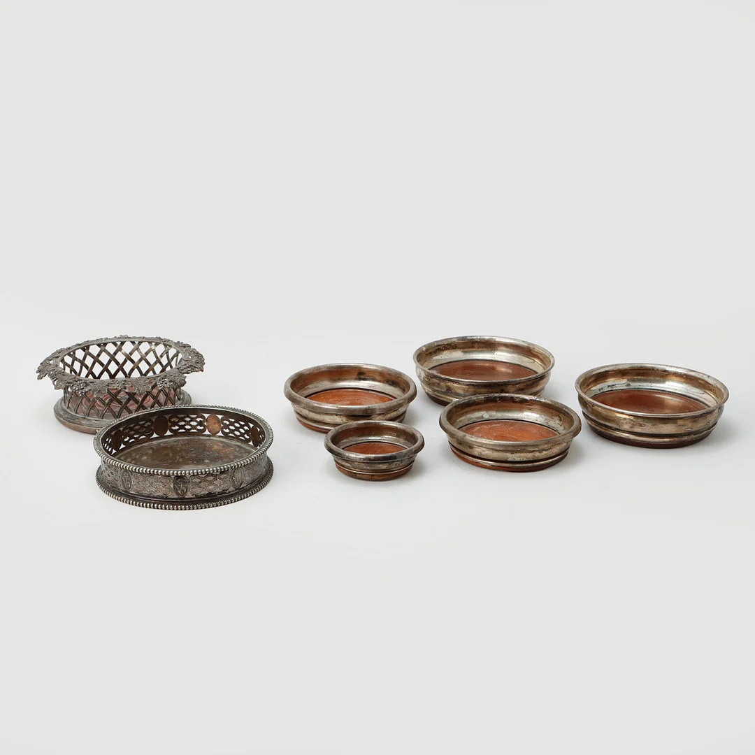 FLASKSTÄLL/COASTERS, 7 st, vitmetall/trä, 18/1900-tal. — Silver plated — Göteborgs Auktionsverk