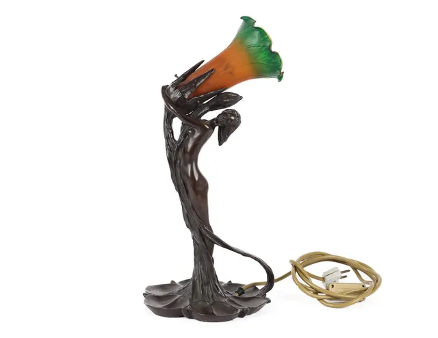 Art Nouveau table lamp in the shape of a woman and plant, patinated metal with a shade of orange and green glass, 20th century.