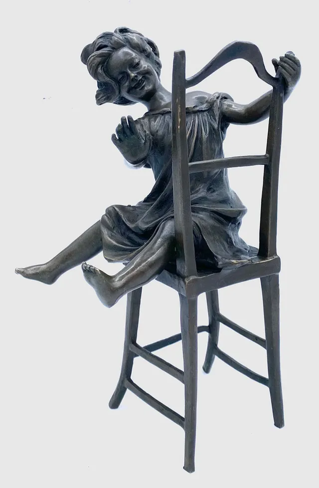 NIÑA SENTADA EN UNA SILLA. BRONCE PATINADO.