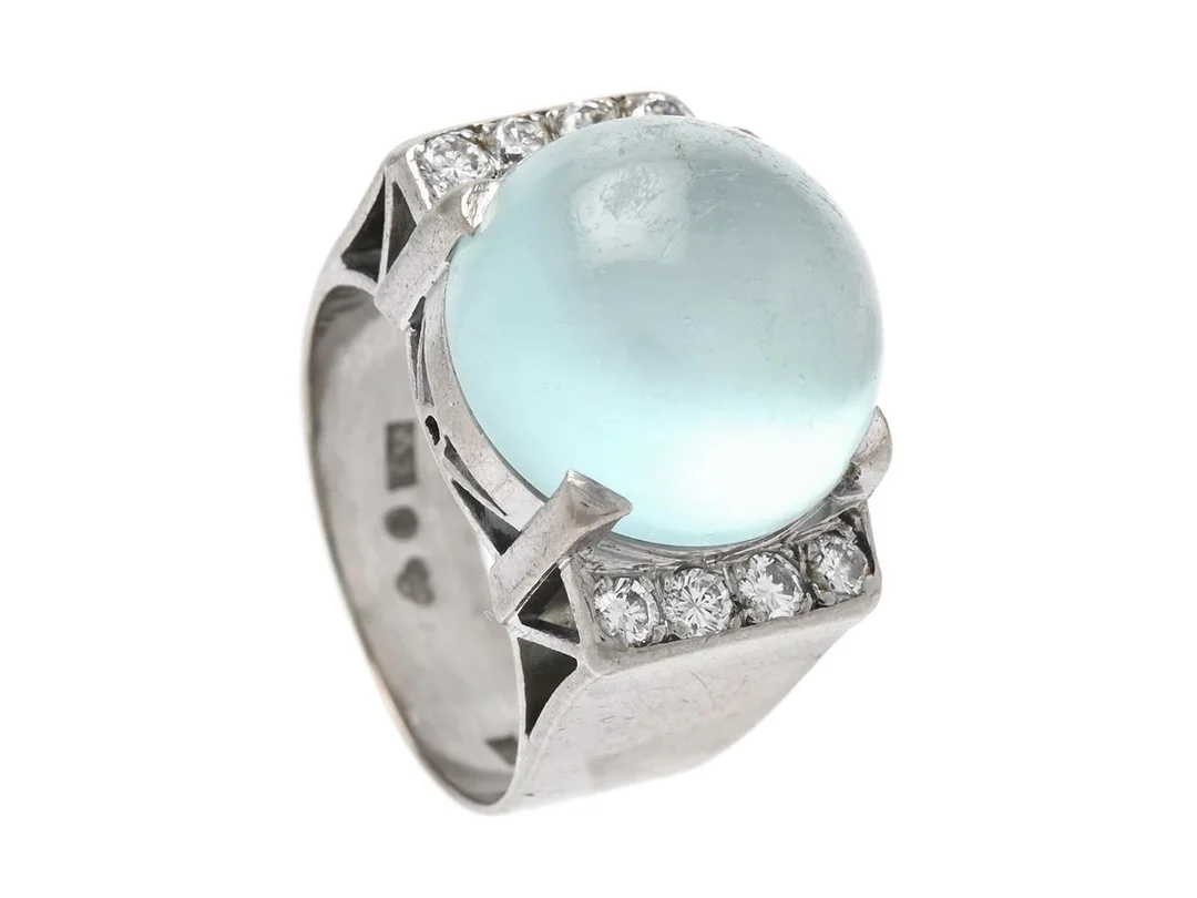 ATELIER AJOUR, ring,18K vitguld, cabochonslipad akvamarin ca 11,0 ct, 8 briljantslipade diamanter ca 0,25 ctv, ca TW/VVS, Stockholm 1957, stl 17 mm, vikt 10,6 g, akvamarinen med slitage. — Smycken/Ring — Kaplans