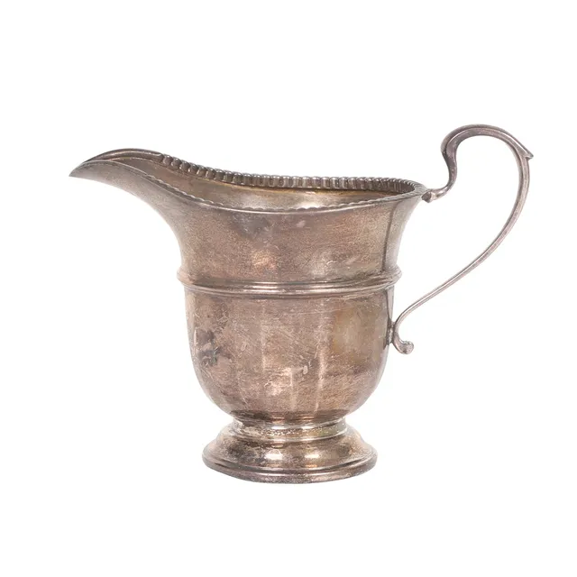 A GEORGE V SILVER CREAM JUG.