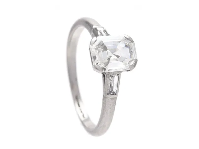 RING, platina, smaragdslipad diamant ca 1,02 ct, ca W(H)/VS1, 2 baguetteslipade diamanter ca 0,10 ctv, stl 16,5 mm, vikt 3,6 g, diamanten med nagg vid rondisten, nedsliten fattning.
