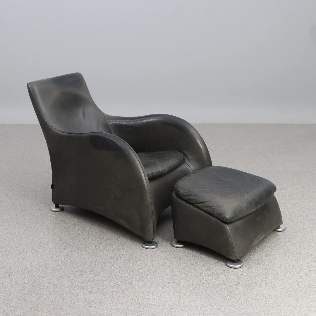GERARD VAN DEN BERG. FÅTÖLJ MED FOTPALL. Svart skinn, fötter i aluminium. "Loge", Montis. Samtida tillverkning. — Armchairs & Chairs — Skånes Auktionsverk