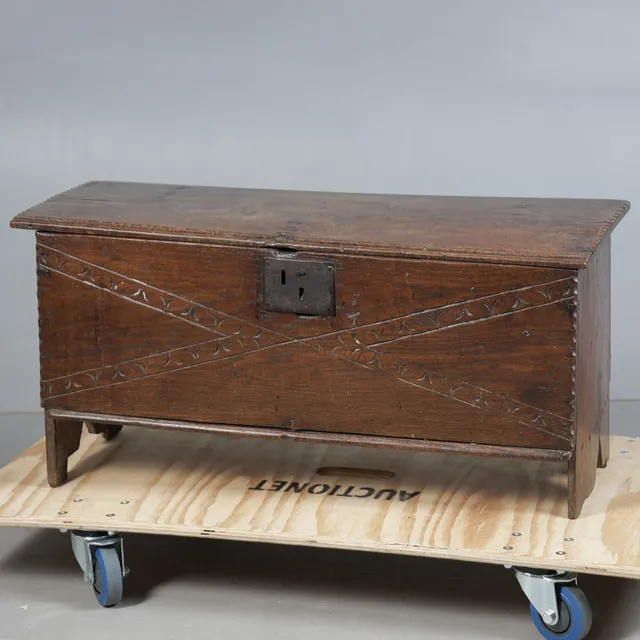 A 17TH CENTURY CARVED OAK BOARDED CHEST.