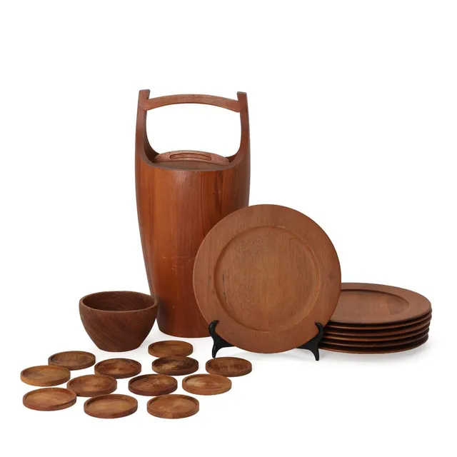Solidt staved teak ice bucket with orange plastic liner. Manufactured and marked by Dansk Designs Denmark, IHQ. H. 48.5. Seven teak cover plates. Marked Wiggers, Denmark. Diam. 28. And a teak bowl and 12 glass coasters. Unmarked. Diam. 8.5–15 cm. (21)