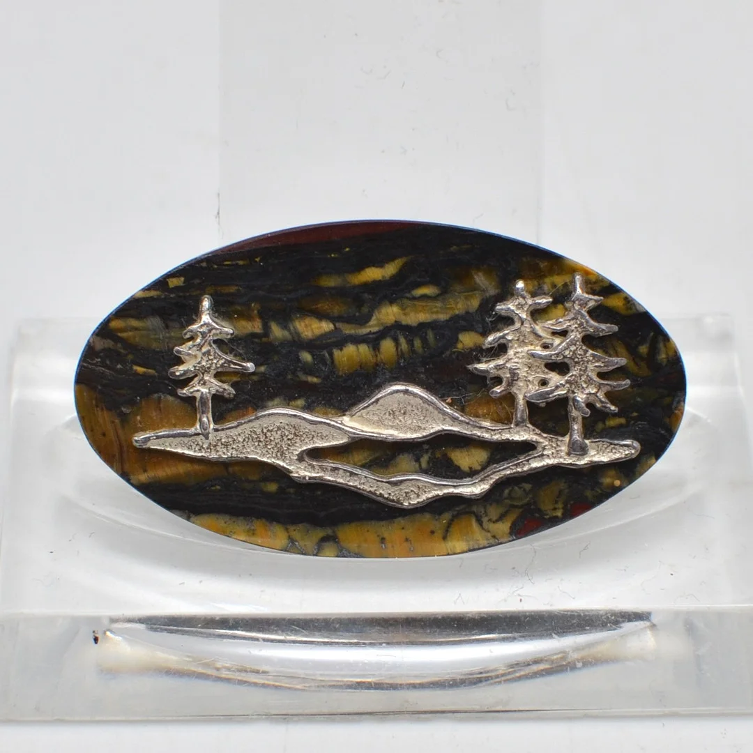 DESIGNERBROSCHE MIT LANDSCHAFTSMOTIV, TIGERAUGE, STERLINGSILBEREINLAGE, RÜCKSEITIG GESTEMPELT, 20. JAHRHUNDERT. — Brooches & Pendants — Kunst- und Auktionshaus Kleinhenz