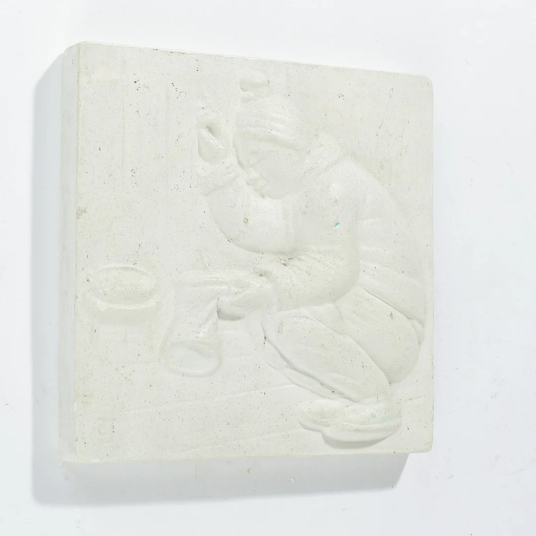Bemalet gipsrelief med motiv af inuit syende en støvle, signeret med monogram af ubekendt billedhugger, 1900-tallets anden halvdel. — Sculptures & Bronzes — Palsgaard Kunstauktioner