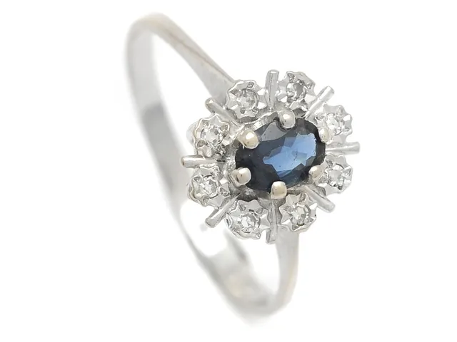 CARMOSÉRING, 18K vitguld, ovalslipad blå safir, 8 åttkantslipade diamanter 0,08 ctv, W/VS enligt gravyr, stl 18,5 mm, vikt 2,6 g.