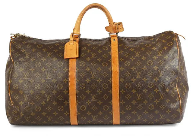 A “Keepall” travel bag of brown monogram coated canvas with brown leather trim, gold-toned hardware, two handles, one buckle on the handle, one luggage-tag, one zipped compartment with brown fabric lining. H. 30 x W. 60 x D. 40 cm. 1993.