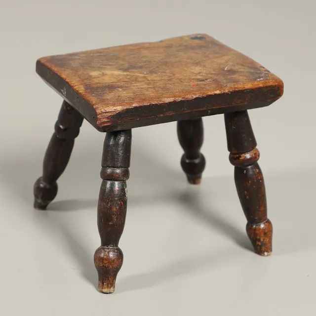 A 19TH CENTURY ELM TOPPED MILKING STOOL.