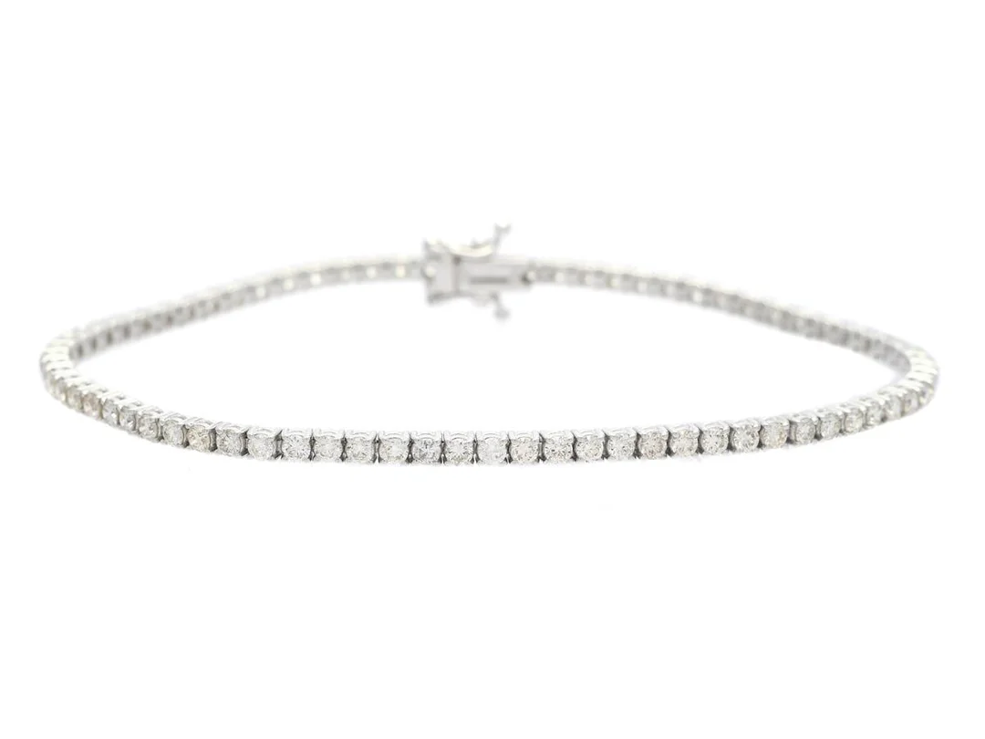 TENNISARMBAND, 18K vitguld, 74 briljantslipade diamanter ca 2,58 ctv, ca W-TCa(H-L)/SI-P, längd 17,5 mm, vikt 7,3 g, ett fåtal diamanter med mindre nagg, något undermålig ledning på ett ställe, en diamant snurrar i fattningen. — Smycken/Tennisarmband — Kaplans