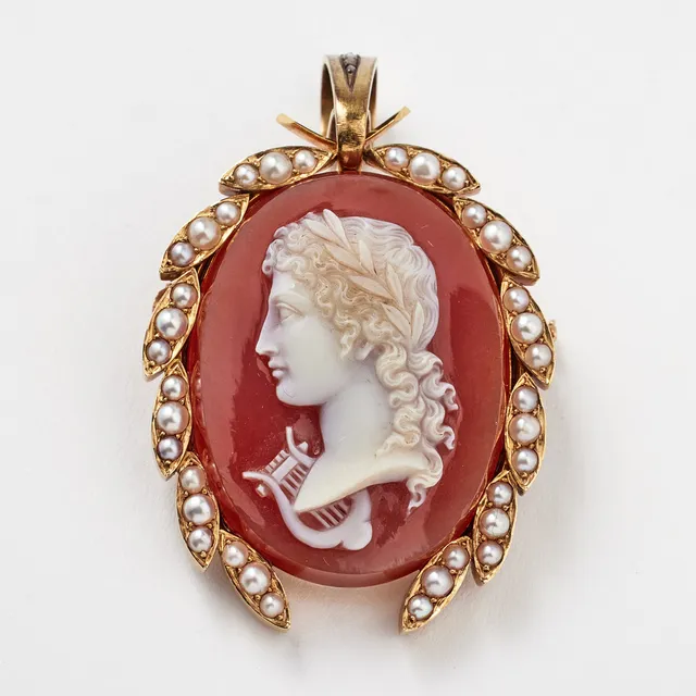 LARS LARSON (1844-1880), brosch/hänge, 18 k guld, röd sardonyx med skuret porträtt av Apollo, avbildad med lagerkrans samt lyra, bård med orientaliska pärlor, upphäng med dekor av rosenslipade diamanter, baksida med gömma.