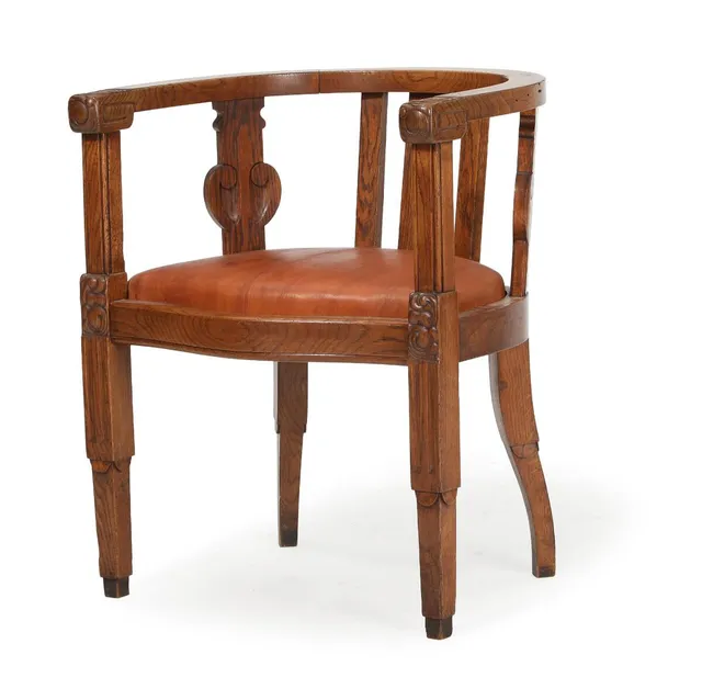 Armchair of solid oak carved with foliage, seat upholstered with nigerhide. Circa 1910.