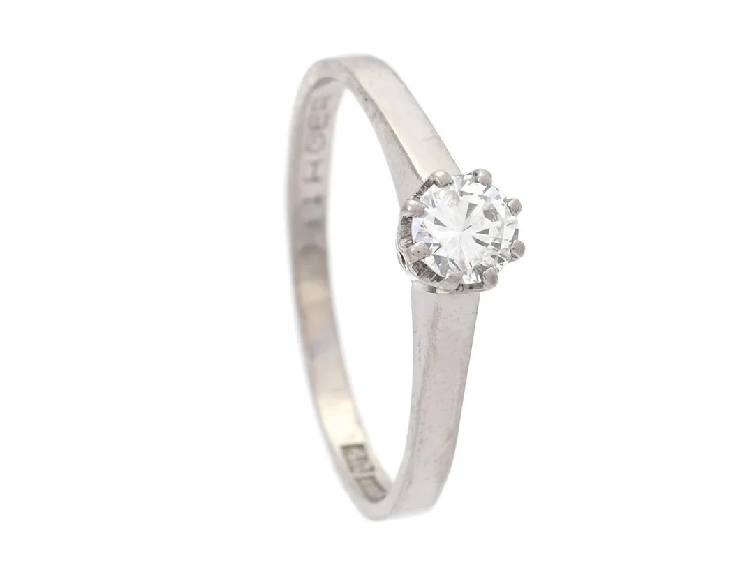 ENSTENSRING, 18K vitguld, briljantslipad diamant 0,41 ct enligt gravyr, ca TW/SI, Nilsmarks Guld & Juveler AB, Göteborg 1970, storlek 19,5 mm, vikt 2,5 g, personlig gravyr, diamanten har låg krona, stort bord, inneslutning som når ytan på paviljongen, mindre kulettnagg. — Smycken/Enstensring — Kaplans