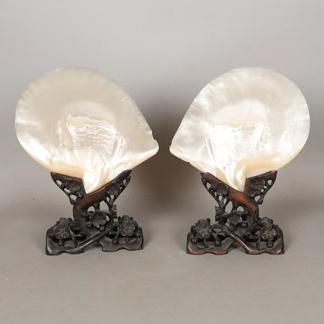 A PAIR OF CHINESE MOTHER-OF-PEARL SHELLS RAISED ON CARVED HARDWOOD BASES (2).