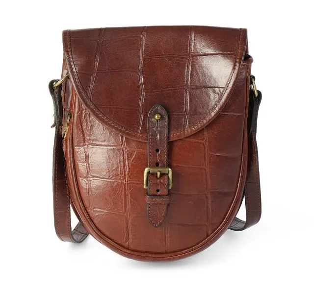 A bag of brown croc-inspired leather with a buckle, golden hardware, an adjustable shoulderstrap, one interior compartment with one zippered pocket and chechered microfiber lining. H. 24 x W. 19 x D. 4 cm.