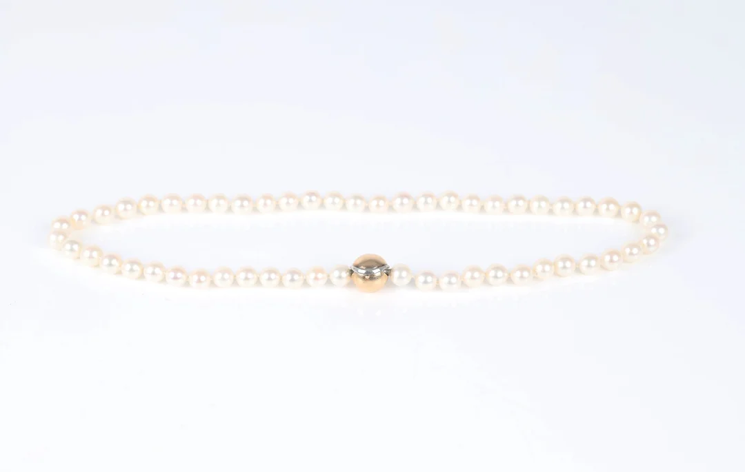 Ole Lynggaard: A 'Smile' clasp of 14k gold and white gold with a pearl necklace. (2) — Jewellery/Necklaces, pendants — Lauritz