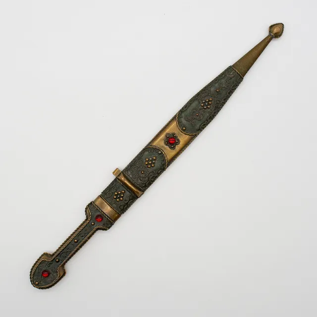 TRADITIONELLER KAUKASISCHER LANGDOLCH (KINDSCHAL), AUS DER KAUKASUSREGION, REICH VERZIERT MIT KUNSTVOLLEN FLORALEN MUSTERN UND DEKORATIVEN ROTEN GLASSTEINEN, FRÜHES 20. JAHRHUNDERT.