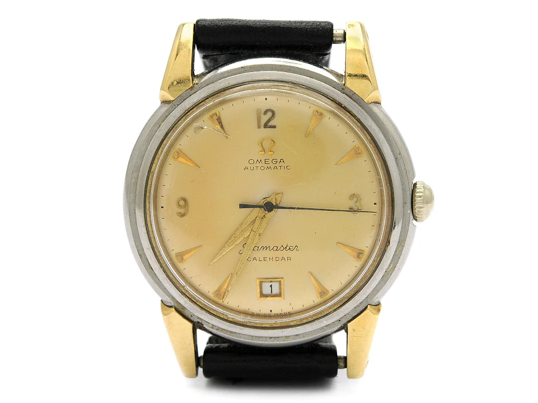 OMEGA, Seamaster Calendar, Cal 353, Serie nr. 12916964, Ref nr. 2627, Boett nr. 2627-7 SC, herrur, 35,5 mm, guld på stål (staybrite), hammarautomat, plexiglas, datum, skadad urtavla, glasring saknas, läderband, ca 1951, box — Klockor/Omega — Kaplans