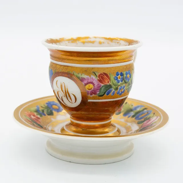 PORZELLAN TASSE MIT UNTERTELLER, ANFANG 19. JAHRHUNDERT FRANZÖSISCH EMPIRE, KARTUSCHE MIT MONOGRAMM, HANDBEMALT, MIT BLUMENDEKOR.