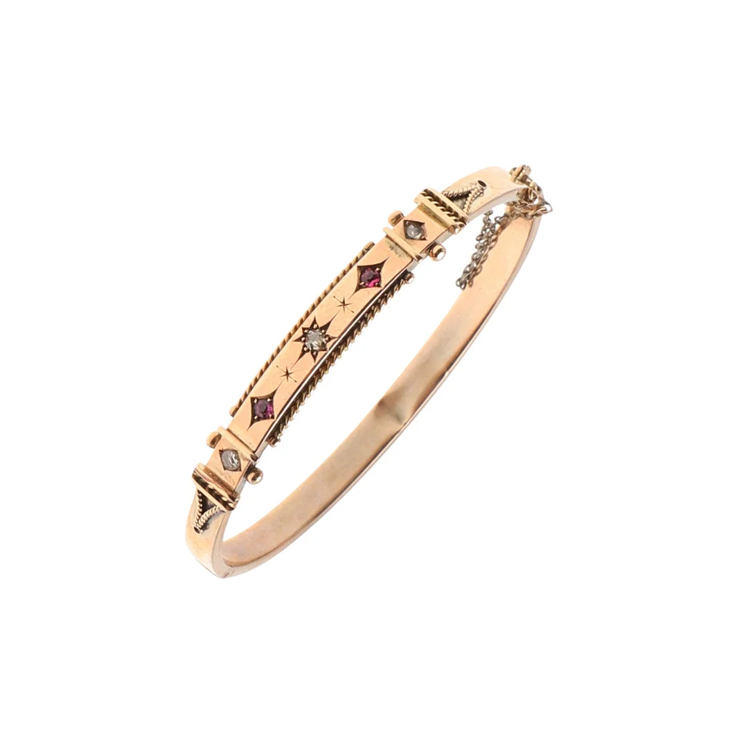 AN EDWARDIAN GOLD AND GEM SET HINGED BANGLE. — Bracelets — Lawrences Auctioneers