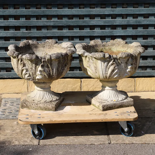 A PAIR OF RECONSTITUTED STONE ACANTHUS LEAF URN PLANTERS.